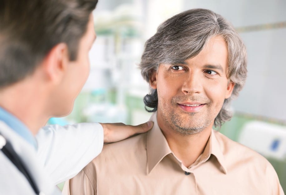 Médico urologista em seu consultório explicando para o paciente, homem por volta 45 anos, sobre como funciona prótese peniana em casos de disfunção erétil.