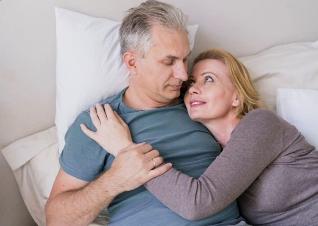 Casal maduro repousa na cama após uso da prótese inflável peniana.